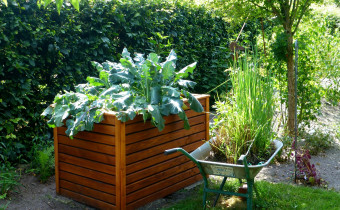 Pflanzkübel mit einer Schubkarre daneben in einem Garten